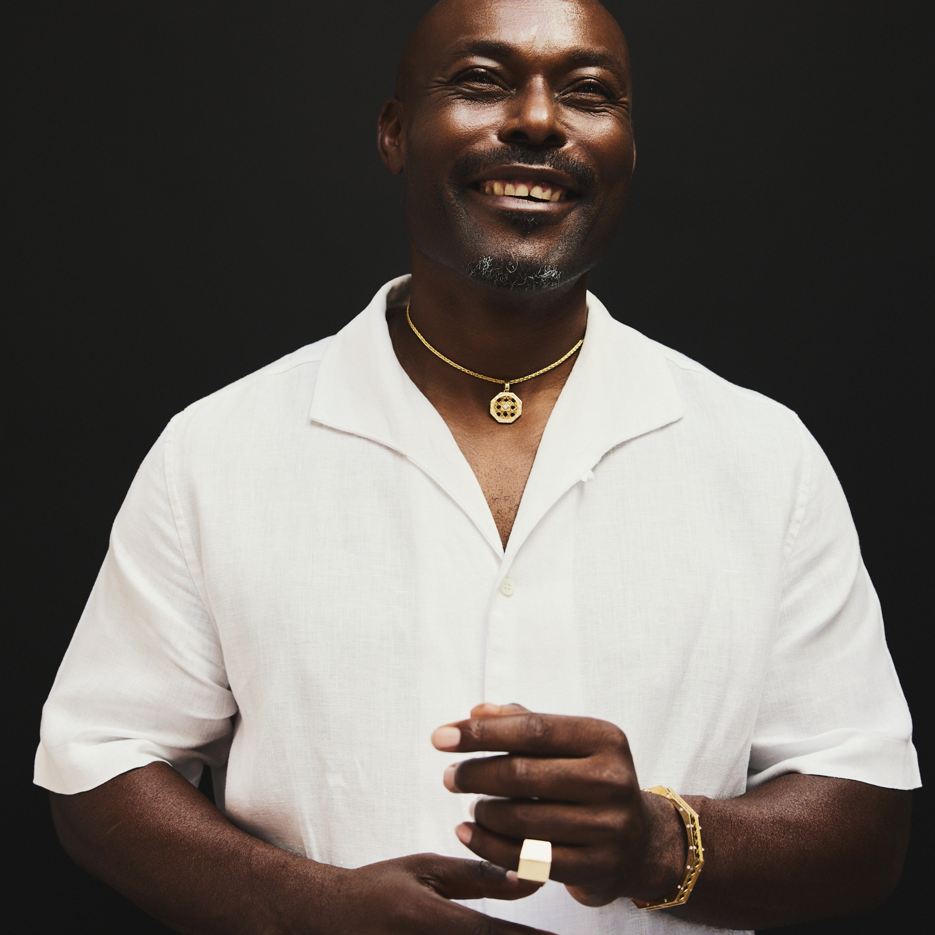 MoAnA LUU fine jewelry worn by Jimmy Jean Louis, featuring Doudou octagonal pendant necklace, Doudou Signet ring and bracelet in 18K yellow gold inspired by Caribbean fish traps.