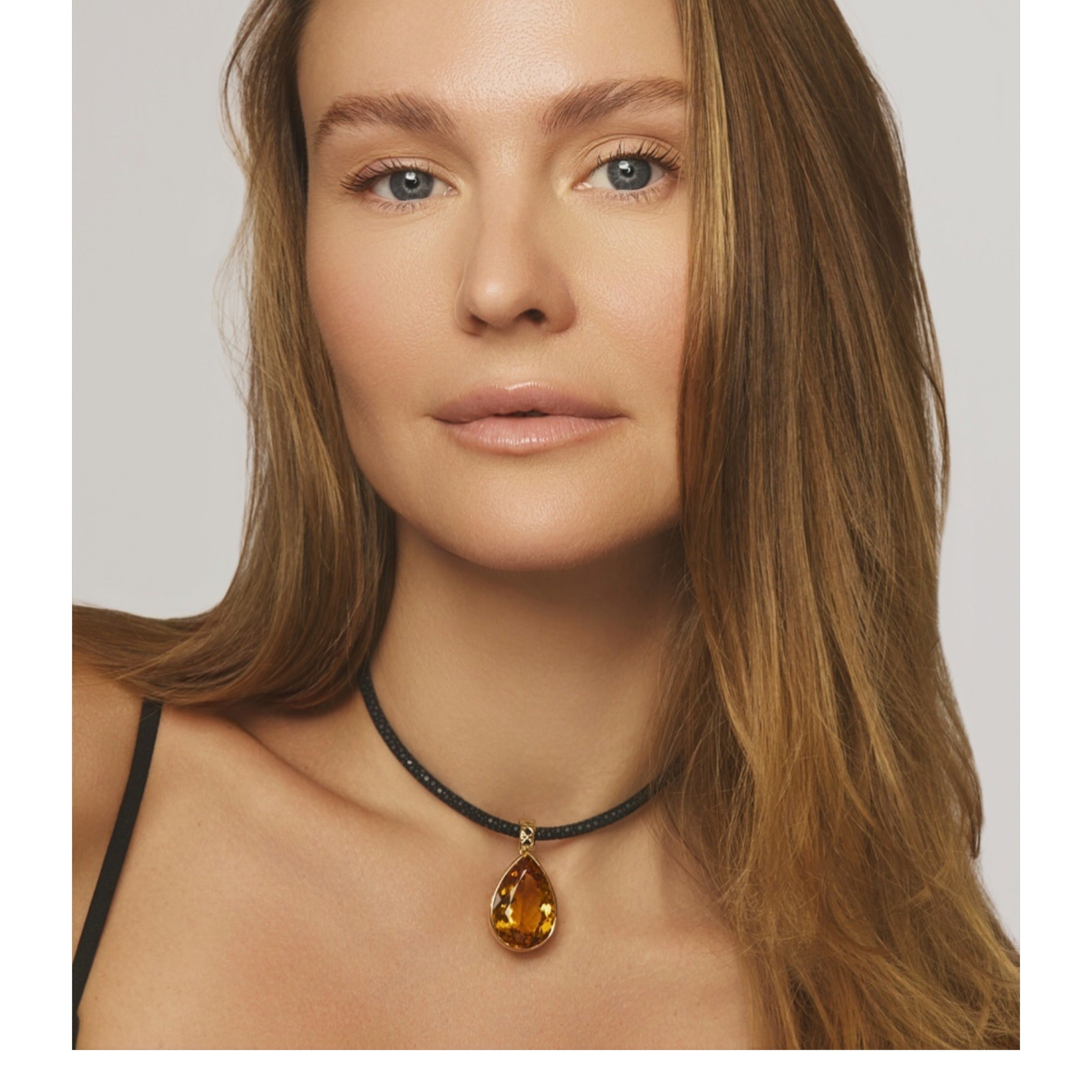 MoAnA LUU Maxi Dlo pear-shaped citrine pendant in 18K yellow gold worn on model, suspended on a black stingray leather choker with cane-woven design inspired by Caribbean fish traps.