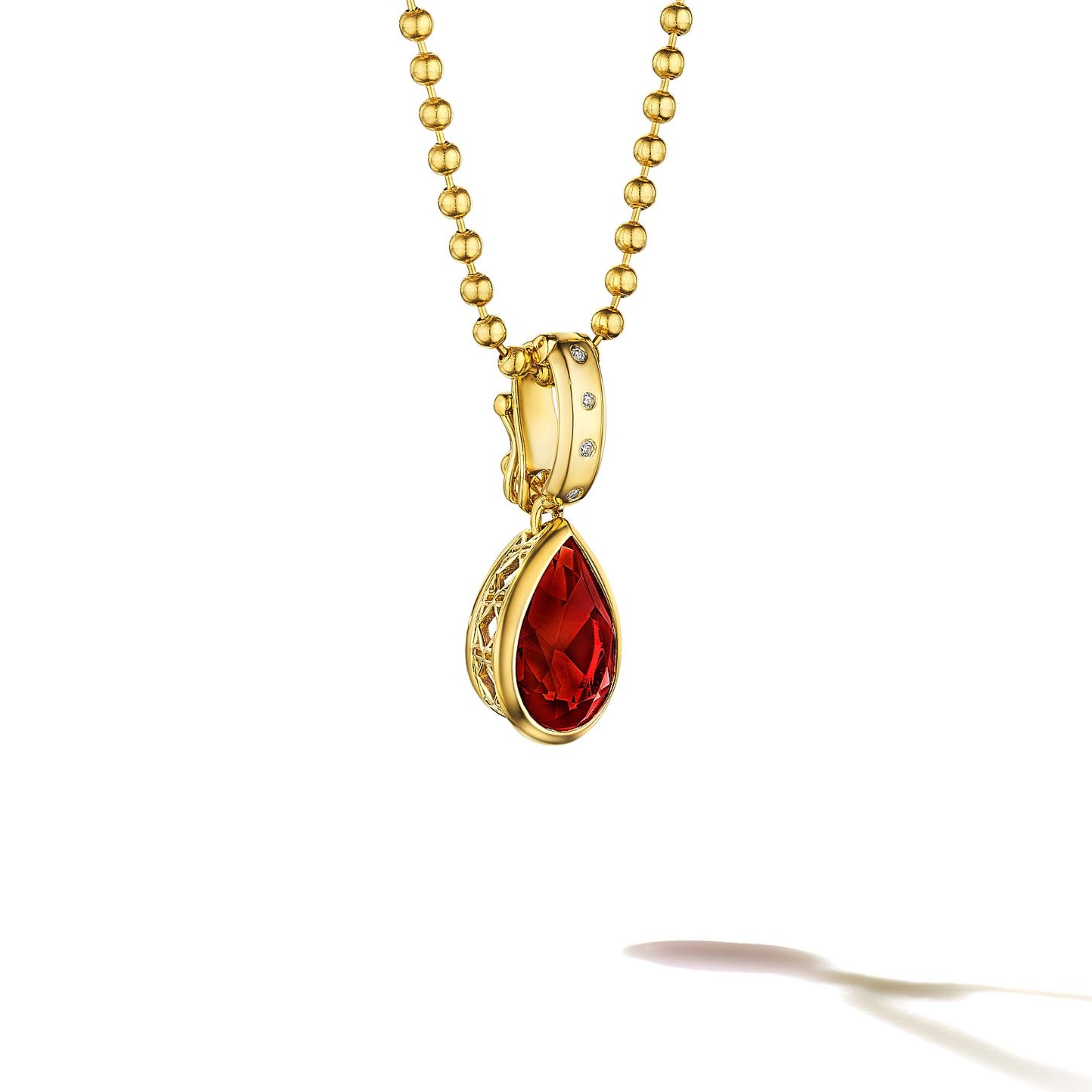 MoAnA LUU Dlo pear-shaped garnet pendant in 18K yellow gold, featuring a cane-woven frame inspired by traditional Caribbean fish traps, reflecting the house’s vision of Creole-inspired fine jewelry crafted in New York.