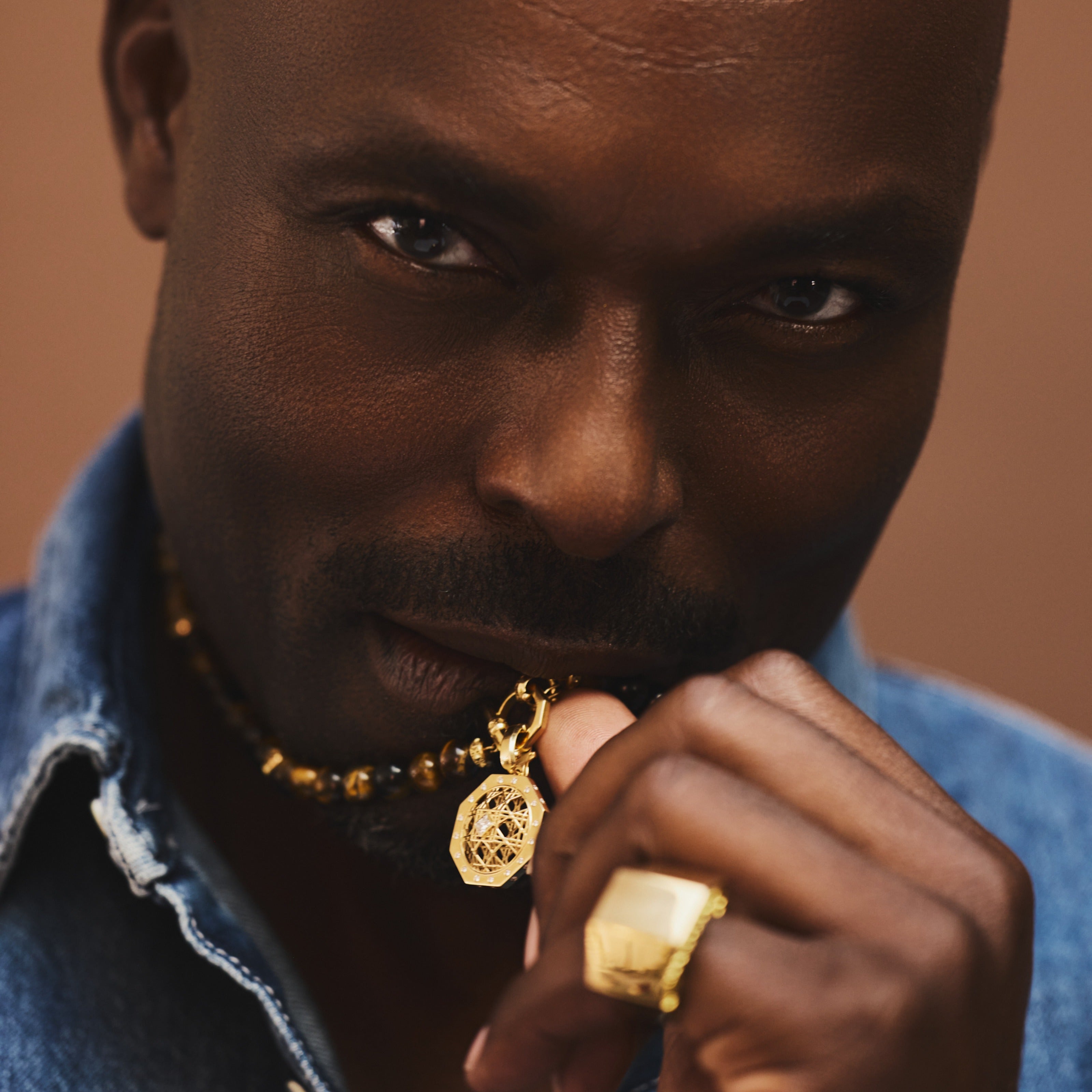 MoAnA LUU fine jewelry worn by Jimmy Jean Louis, featuring Doudou octagonal pendant necklace, Doudou Signet ring and Yva beads in tiger eye.
