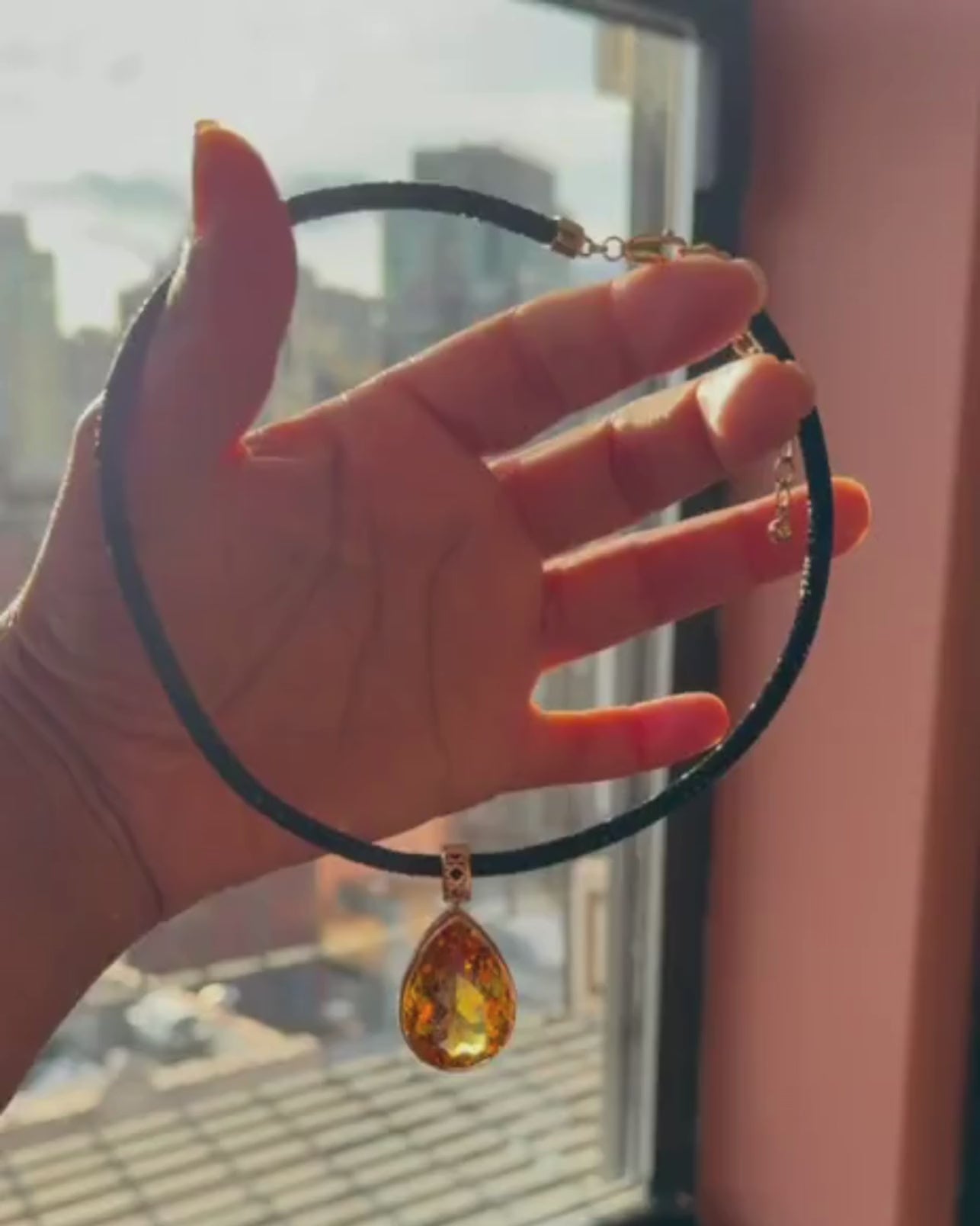 MoAnA LUU Maxi Dlo pear-shaped citrine pendant in 18K yellow gold held by hand, showcasing sculptural cane-woven design inspired by Caribbean fish traps.