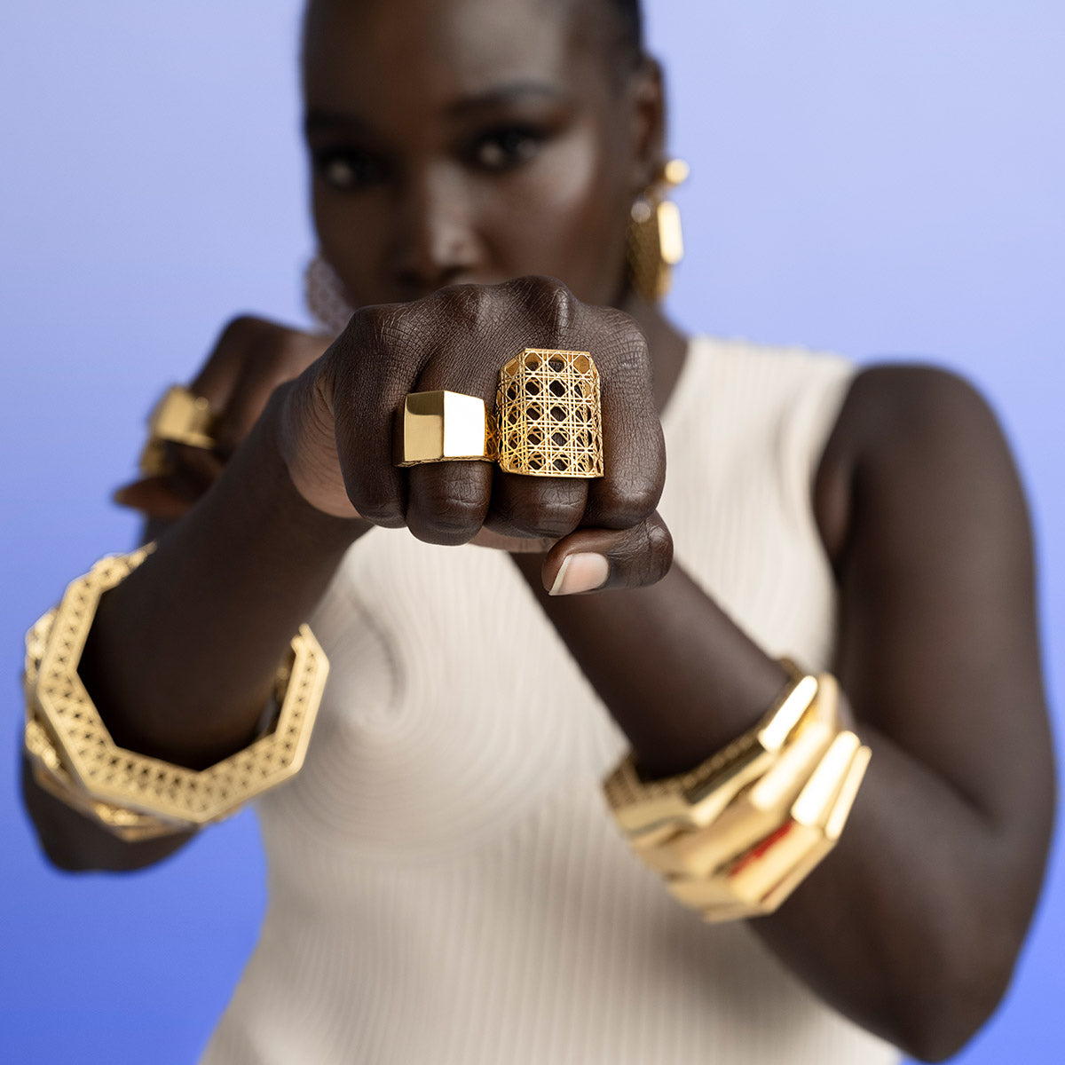 Model wearing MoAnA LUU Doudou bangle bracelets, paired with Doudou Maxi and Signet rings inspired by Caribbean fish traps.